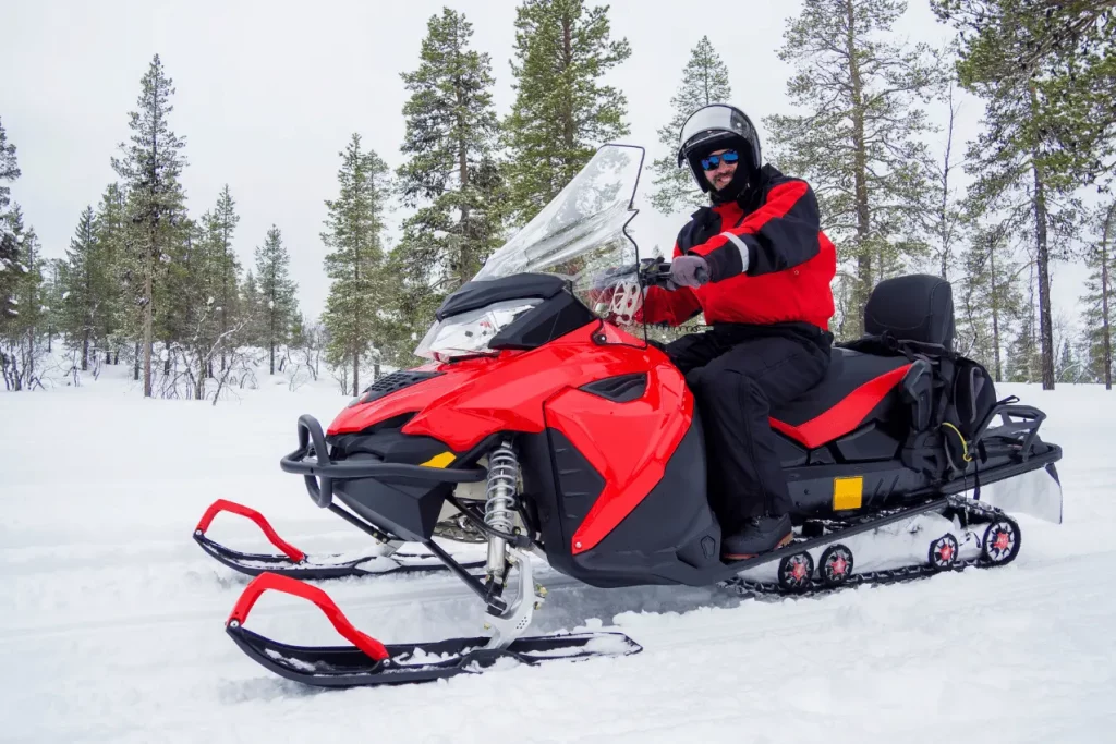 Man riding red quad bike on snowy mountain trail during snowmobiling Poconos adventure