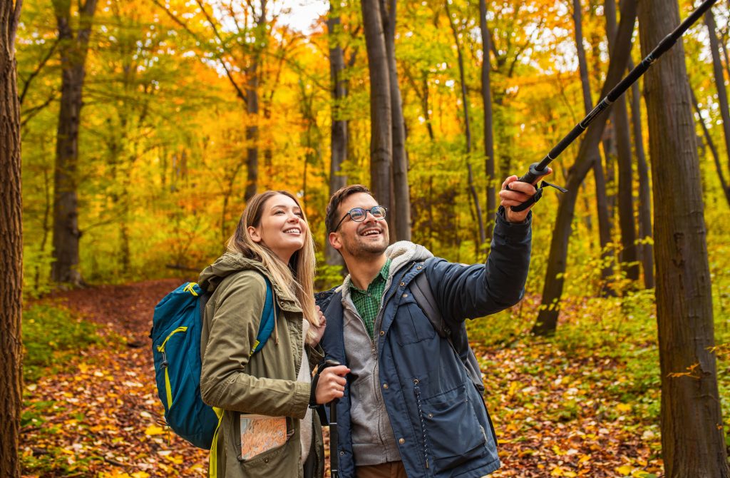 A couple clicking a selfie with beautiful fall colors in the background